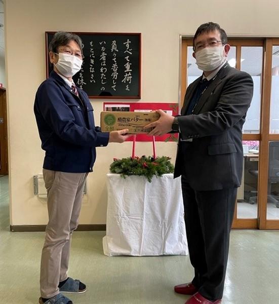 秋田県牛乳普及協会事務局長（右）から「秋田婦人ホーム」施設長（左）へバターを提供の内容を表示