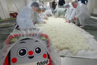 “けいきゅん”が見守るなか、蒸した米をほぐし冷ましていますの内容を表示