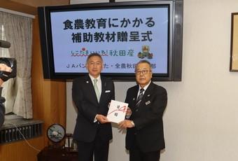 小林県本部長（右）から猿田副知事へ目録を贈呈の内容を表示