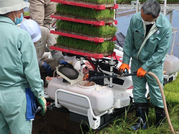 ２段施肥機能を搭載した田植機に水稲用ペースト肥料を入れる関係者らの内容を表示