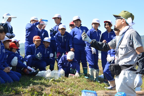 生徒たちに田んぼにいる生きものを説明する山崎講師（左）の内容を表示