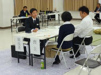 喪家とアイコンタクトを取りながら受付を進める競技中の早川さん（左）の内容を表示