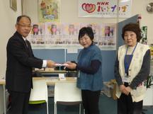 寄付金を手渡す西村副本部長（左）の内容を表示