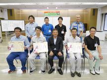 お客様への提案技術を競い合った選手と藤井松太郎大会委員長（前列中央）の内容を表示