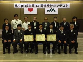 最優秀賞の高木裕元さん（前列中央）と担当者（前列）・審査員の方々（後列）の内容を表示