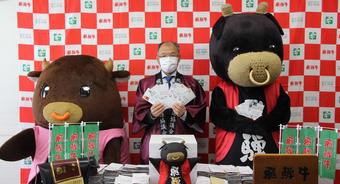 当選者50人を選ぶ、西村寿文飛騨牛銘柄推進協議会幹事長(JA全農岐阜の県本部長:中央)と飛騨牛のゆるキャラ「ひだくろ」(右)、「ひだもも」(左)の内容を表示