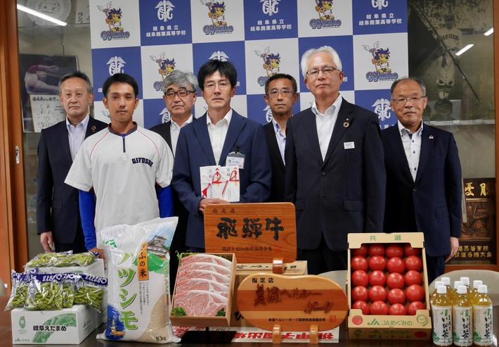 村山校長(前列中央)に県産農畜産物などを贈った岩佐組合長(後列左から2人目)、佐伯常務(同左)、山内会長(前列右)、西村県本部長(後列右)の内容を表示