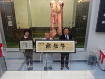 最優秀賞を受賞した松木新一さん（右）と購買者の㈱丸明（中央、左）の内容を表示