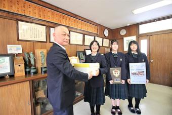 甲子園に出品した飛騨牛を贈る今井畜産部長（左）と学生の内容を表示