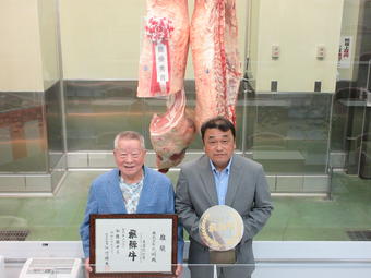 購買者の㈱丸明(左)と最優秀賞を受賞した㈲辻畜産(飛騨牛フェスタin飛騨)の内容を表示