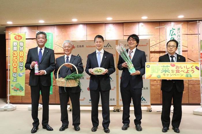 湯崎知事（左から３人目）にわけぎを使った「わけぎと豚バラのガーリックレモン炒め」をアピールした（広島市で）の内容を表示