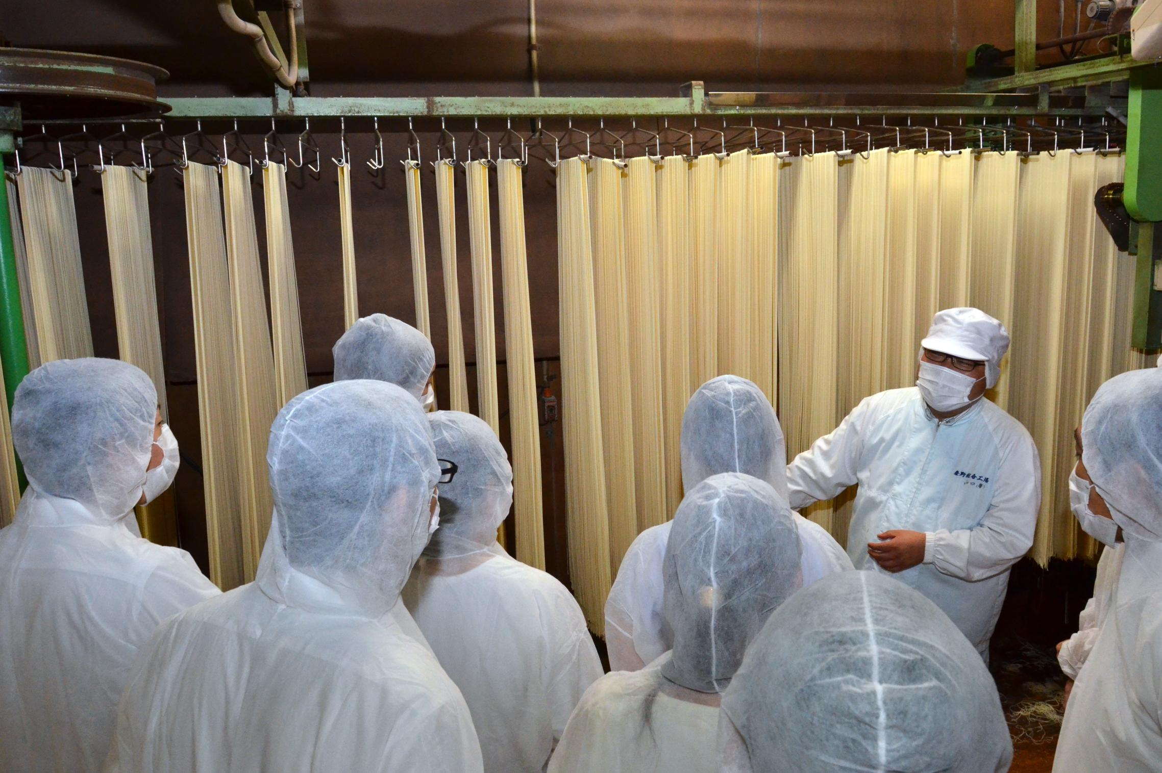 乾麺の乾燥室の衛生管理状況を視察する参加者たち
