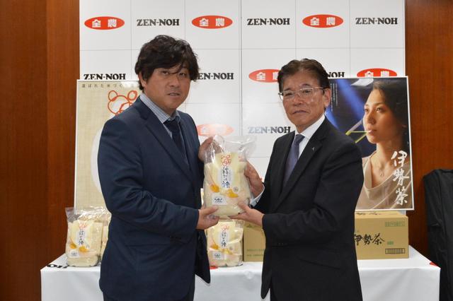 山本県本部長から（右）小山代表に県産品を手渡し激励の内容を表示