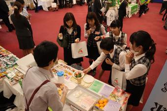 試食しながら商品の説明を聞くJA女性購買担当者らの内容を表示