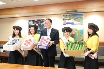 県産青果物を手に報道陣の写真撮影に応える知事とフルーツレディーの内容を表示