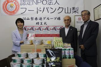 目録を手にした米山理事長（左）と食料品を寄贈した關本会長（中央）と小池副会長（右）の内容を表示
