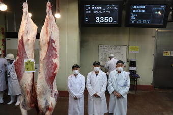 「金賞」を受賞した肉牛と生産者の原氏（中央）、梶原実行委員会会長（左）の内容を表示